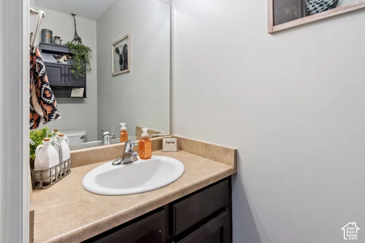 Vanity with integrated sink, laminate countertop, and dark wood-finish cabinetry