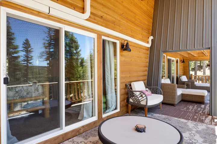 Expansive outdoor deck with wood-finish flooring, featuring natural wood siding and a corrugated metal accent wall