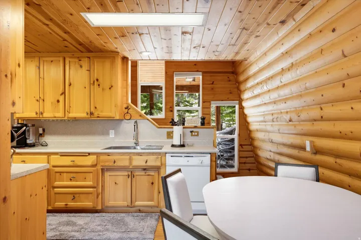 Kitchen featuring extensive wood paneling, wood cabinetry, a stainless steel sink, and white countertops