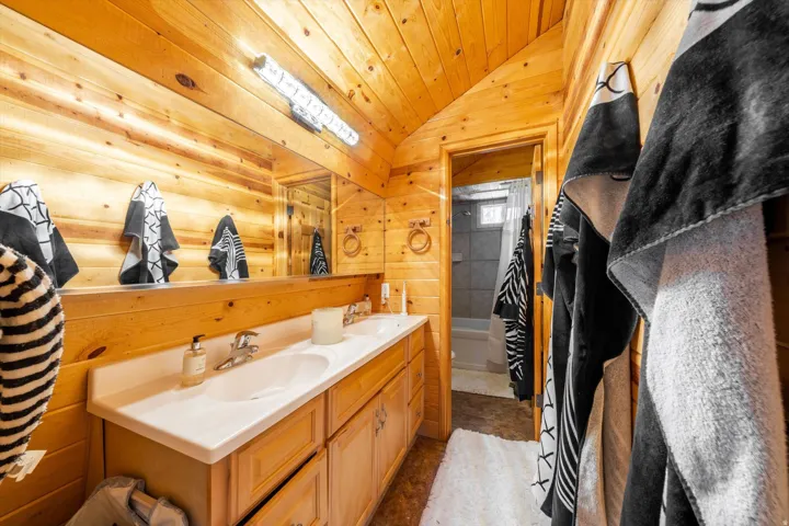 Double vanity with integrated sinks, wood-finish cabinetry, and a full-width mirror