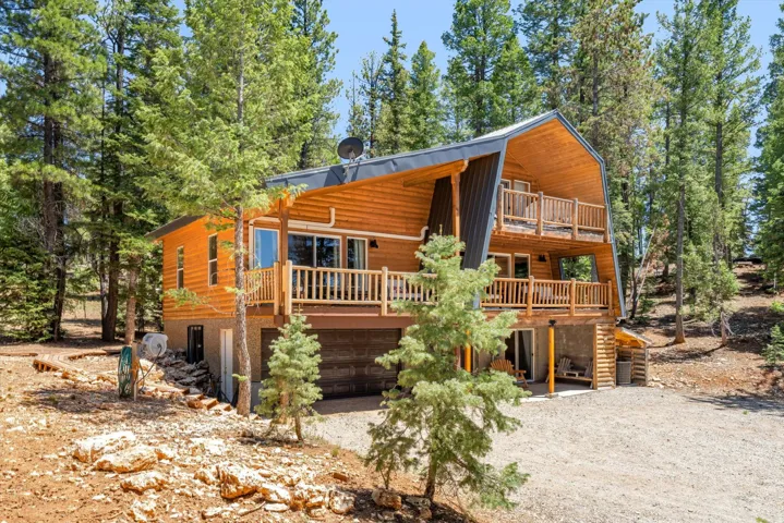 Cabin-style architecture featuring wood siding, a dark metal roof, and multiple wood-railed balconies