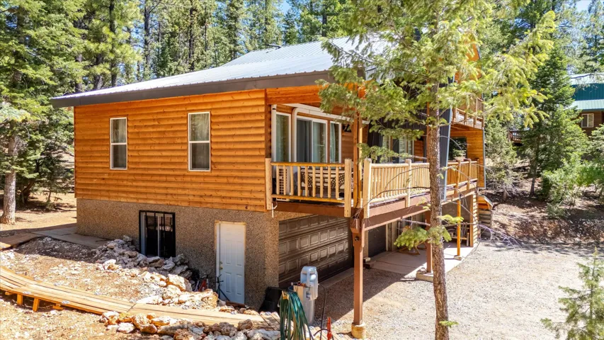 Wood-sided exterior featuring multiple balconies with natural wood railings, a metal roof, and a ground-level garage