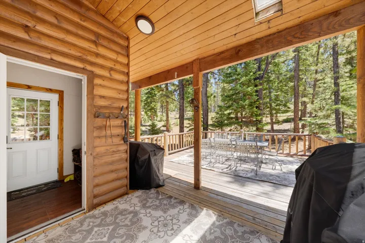 Expansive wood deck with natural wood railing, surrounded by mature pine trees