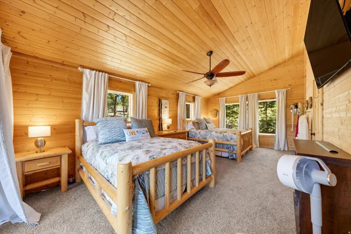 Room featuring wood-paneled walls and ceiling, vaulted ceiling, recessed windows, and a ceiling fan with integrated lighting