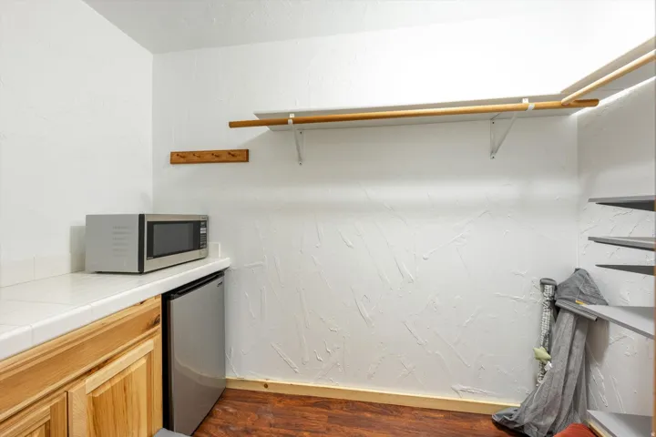 Walk-in closet featuring built-in shelving, wood-finish flooring, and a countertop with natural wood cabinetry