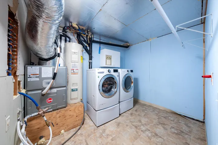 Dedicated utility area featuring a water heater, heating and cooling system, and durable flooring