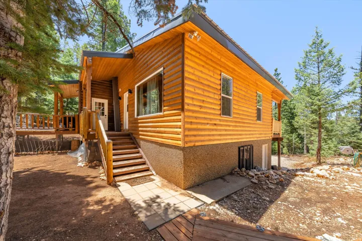 Wood-sided exterior featuring a covered porch, outdoor staircase, and multiple windows
