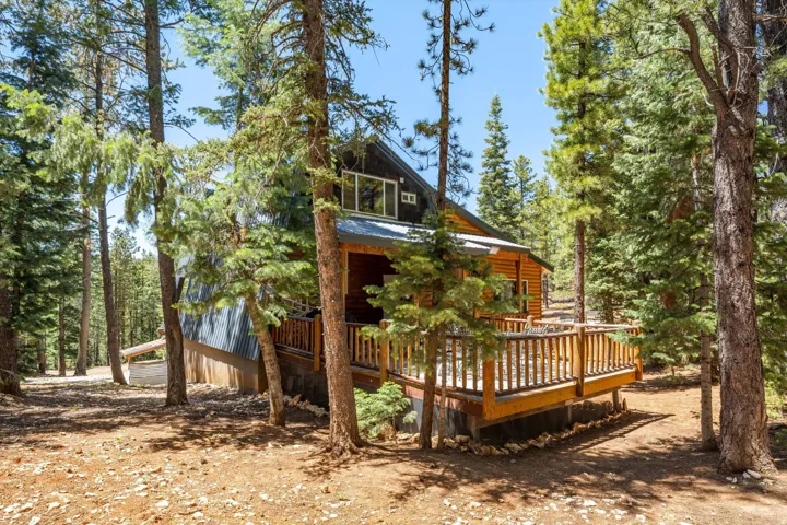 Wood-sided cabin featuring a raised wood deck with a railing system