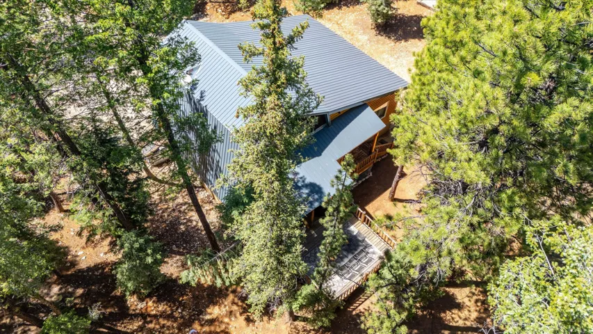 Wood-clad exterior home featuring a gray metal roof, covered porch, and a raised exterior deck