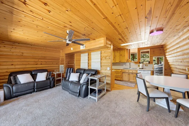 Interior featuring wood paneling, wood-finish flooring, a ceiling fan, kitchen cabinetry, and a dining area