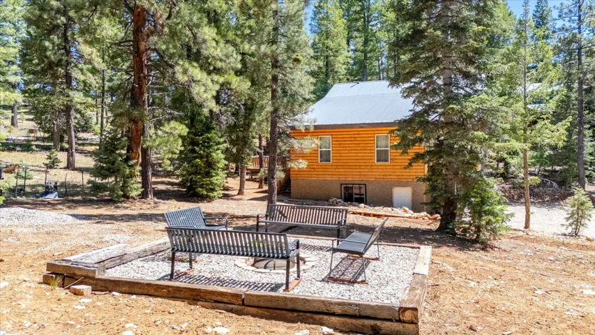 Private fire pit area with gravel groundcover and wood beam border, surrounded by mature trees