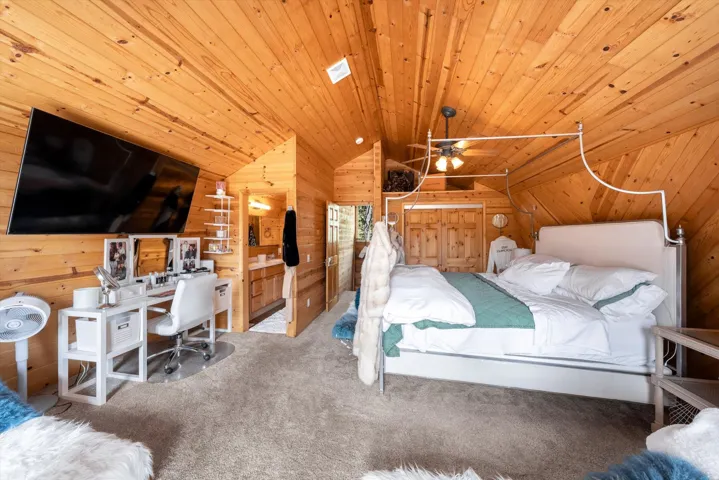 Slanted wood-paneled ceilings and walls define this room, featuring light-toned wood finishes throughout