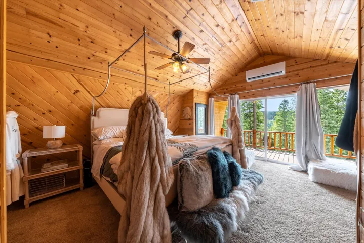 Wood-paneled room with vaulted ceilings, a ceiling fan, and a mini-split HVAC unit