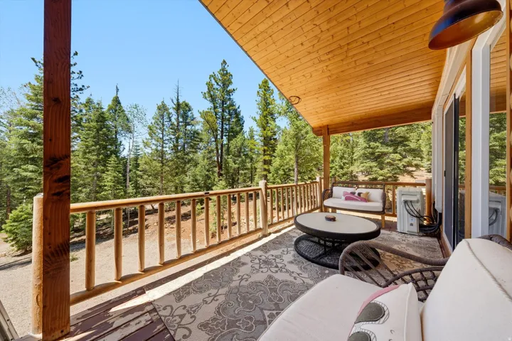 Covered outdoor deck featuring natural wood railing and ceiling