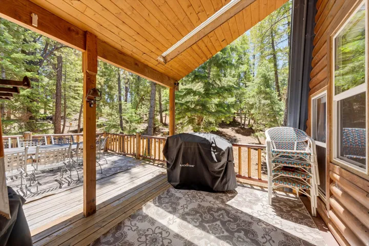 Expansive wood deck with a natural wood railing, featuring a wood-finish ceiling and a log cabin-style exterior wall