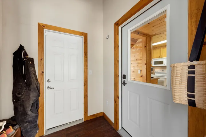 Entryway featuring a white paneled door with wood trim, wood-finish flooring, and a second door with a prominent window