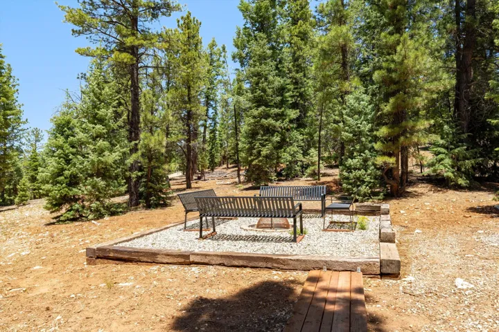 Outdoor fire pit area with gravel groundcover, surrounded by natural wood retaining timbers