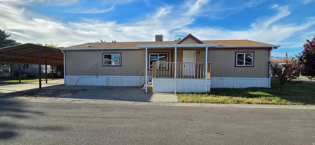 Single-story property featuring a covered front porch with railings, a paved driveway, and an attached carport