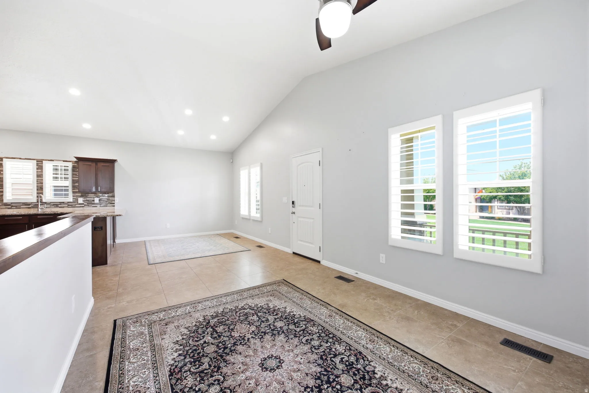 Open-concept living area featuring a vaulted ceiling with recessed lighting and a ceiling fan