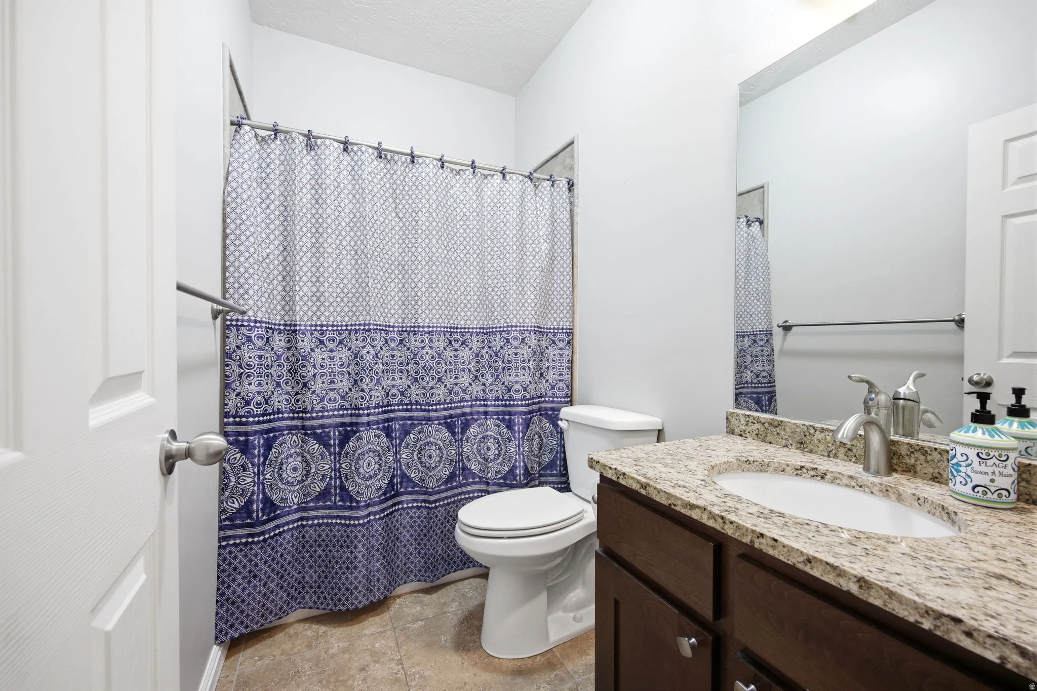 Bathroom vanity featuring a light granite countertop with an undermount sink