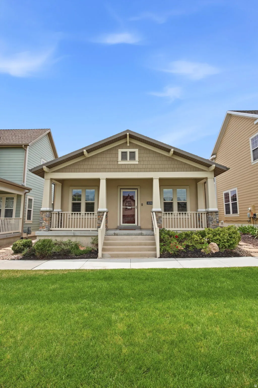 Craftsman-style facade with a covered front porch featuring stone-clad columns and a central front door