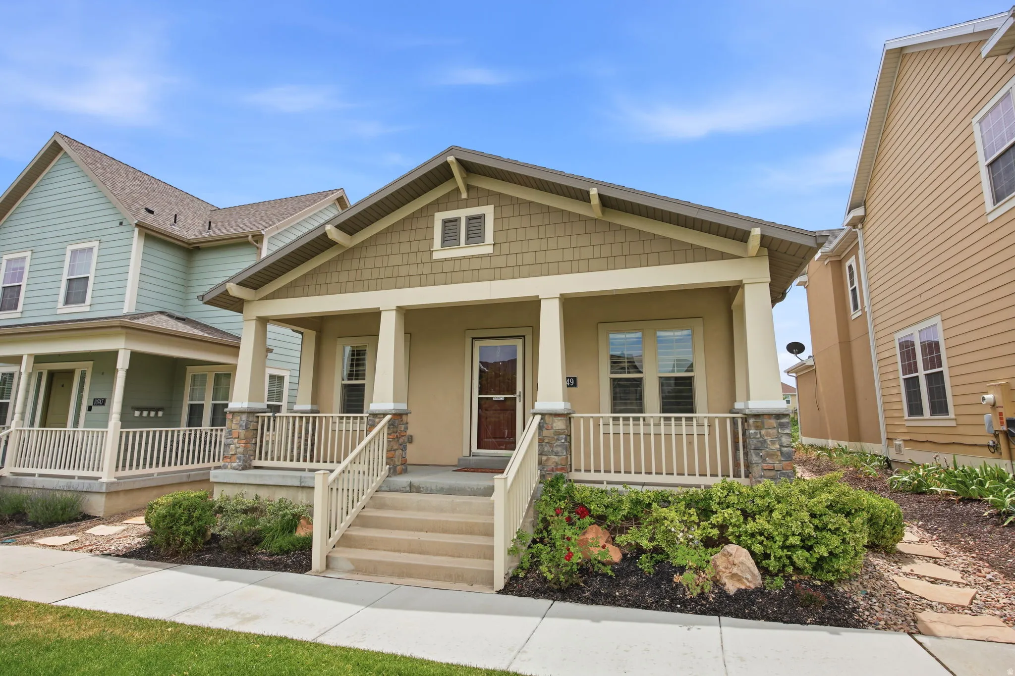 Craftsman-style home featuring a covered front porch with stone accents and a neutral stucco exterior