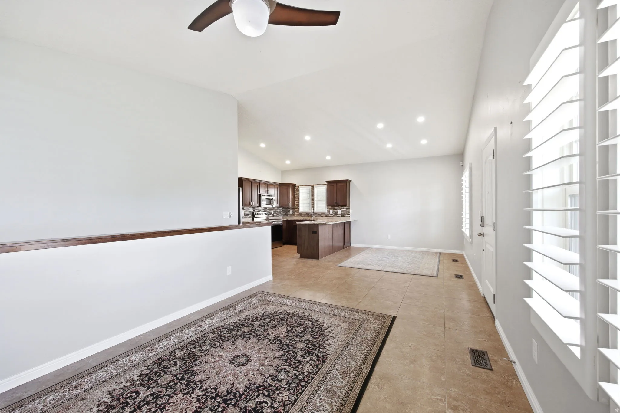 Bright interior with vaulted ceilings, recessed lighting, and a ceiling fan