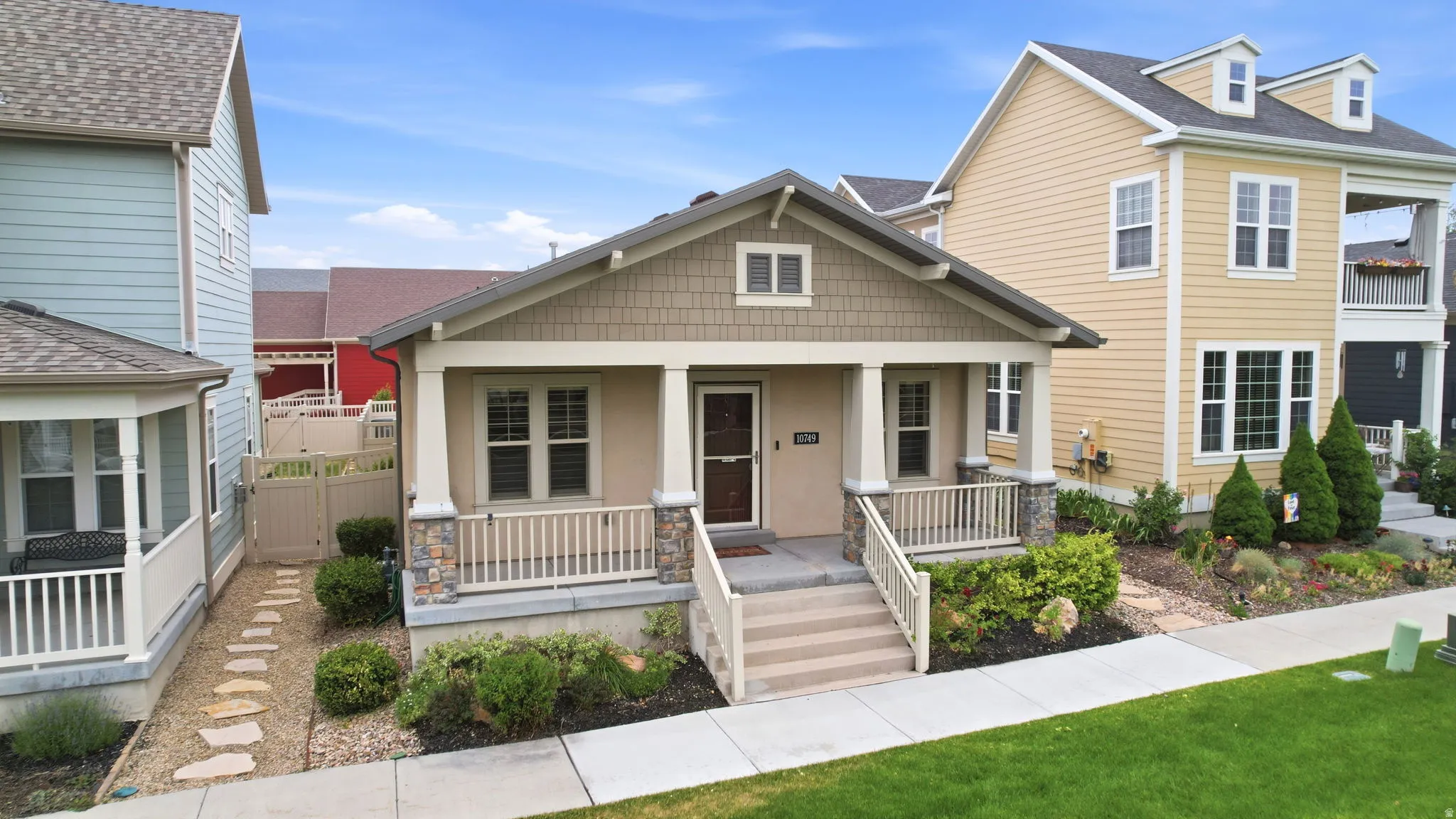 Craftsman-style home featuring a covered front porch with stone-clad columns and a light-toned wood-look door