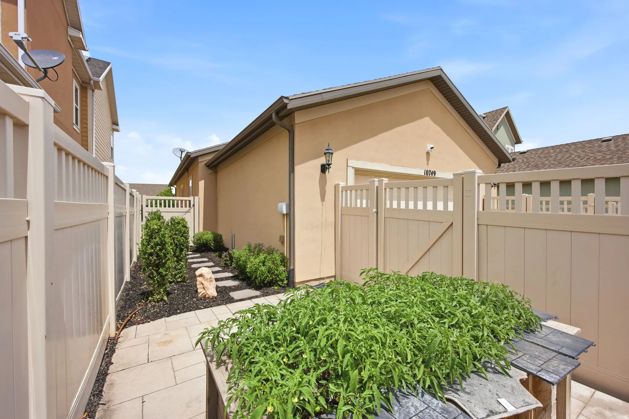 Paved stone pathway leading to a private side entrance with a light beige privacy fence