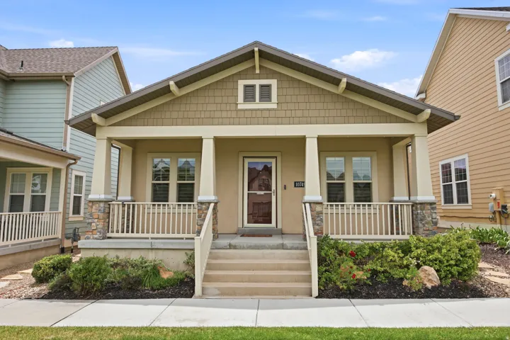 Craftsman-style facade with a covered porch, stone accents, shingle siding, and a prominent gable