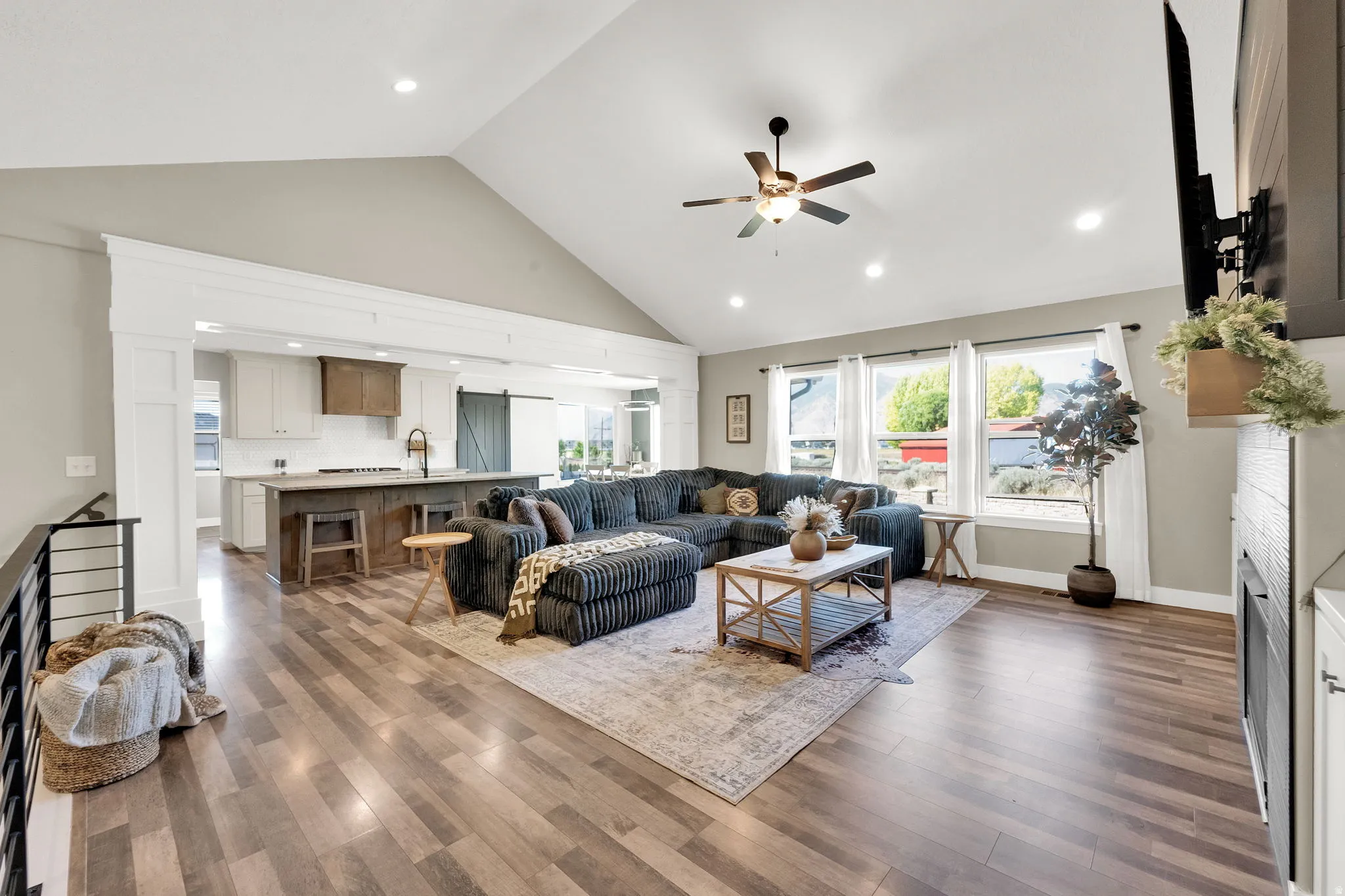Spacious living area featuring vaulted ceilings, wood-finish flooring, and multiple windows