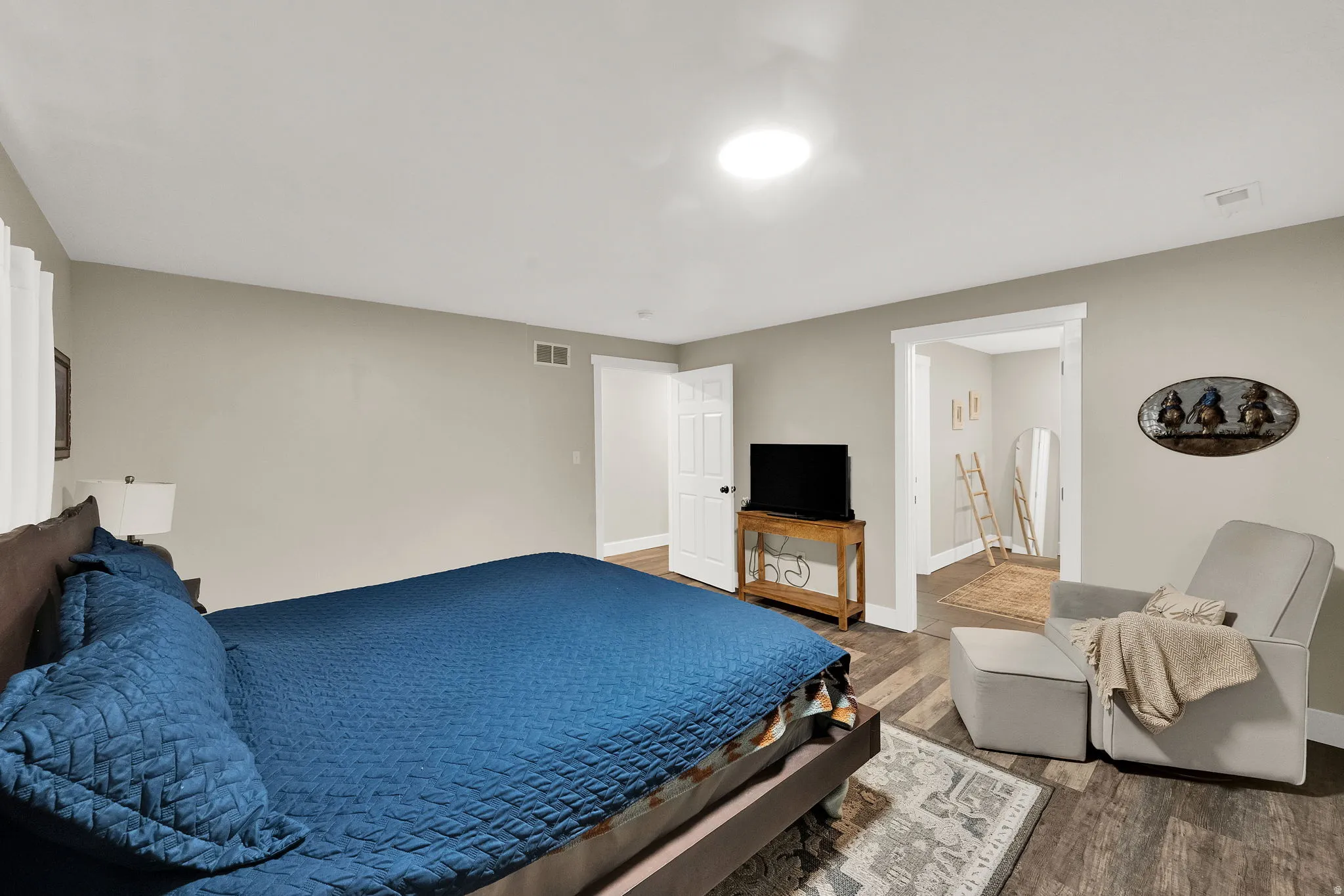 Spacious bedroom featuring wood-finish flooring, neutral wall paint, white trim, and a recessed ceiling light