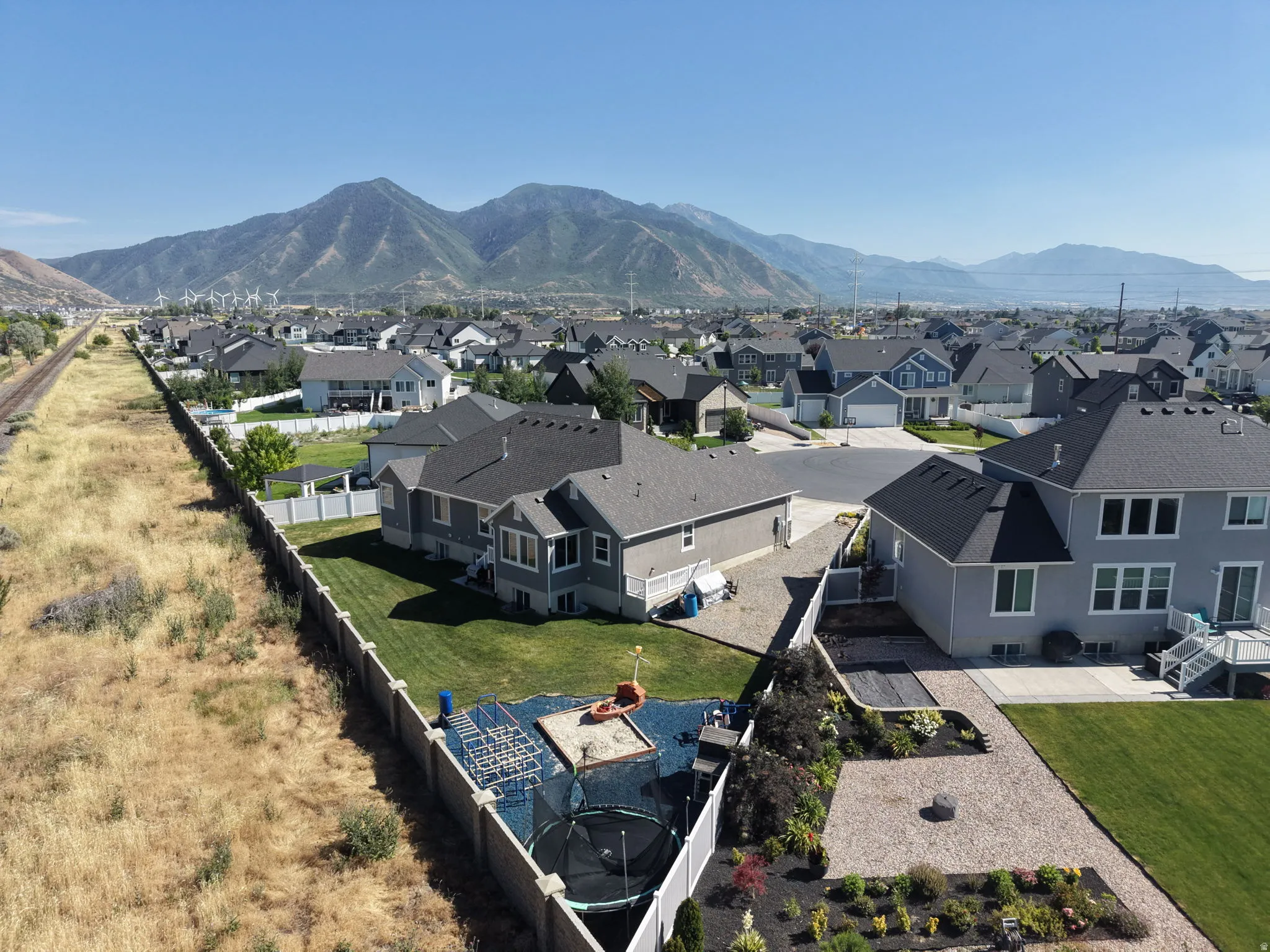 Expansive backyard featuring a green lawn, gravel-covered areas, and a landscaped garden bed
