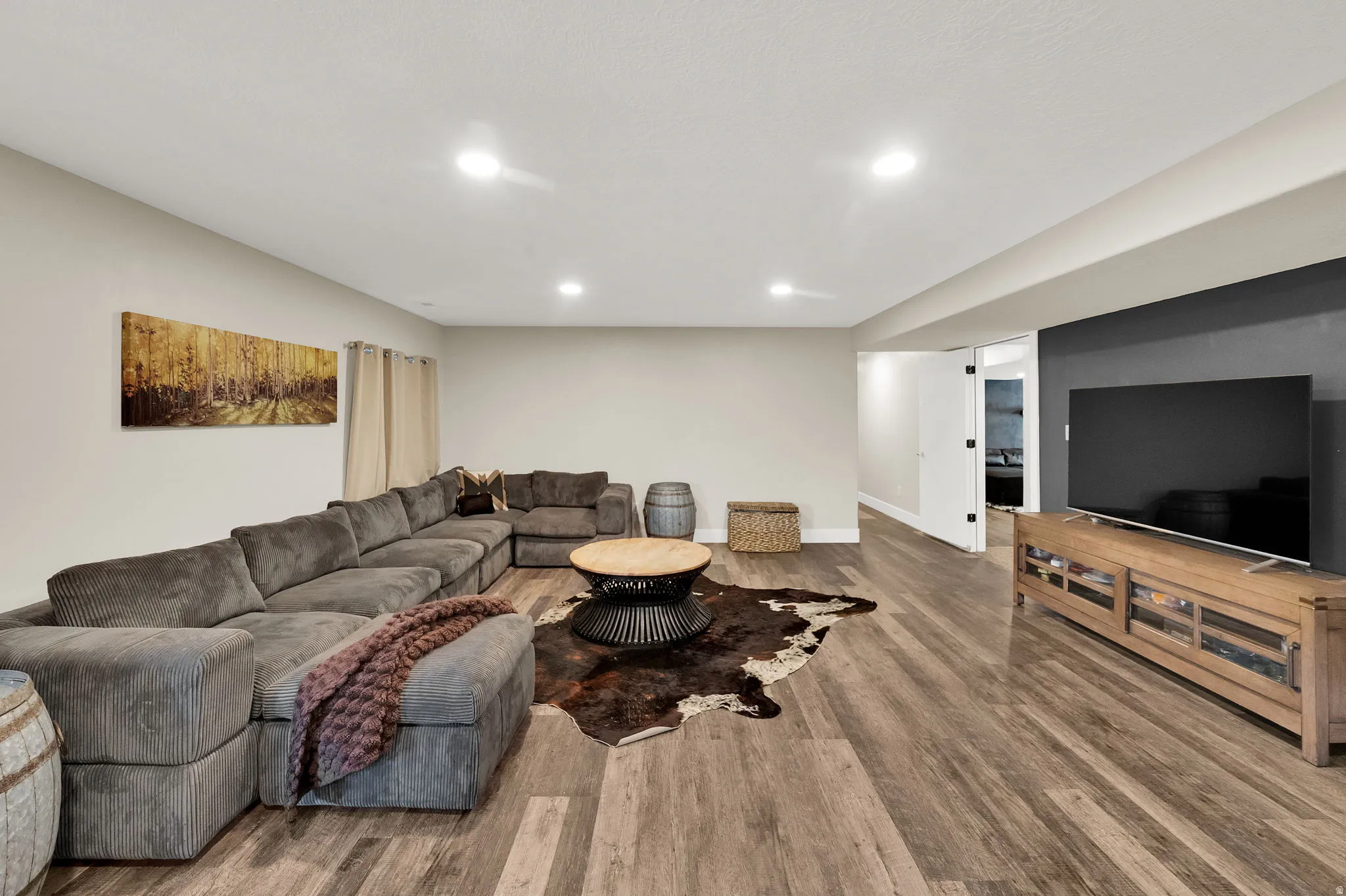 Spacious entertainment area featuring wood-finish flooring, recessed lighting, and a dark accent wall