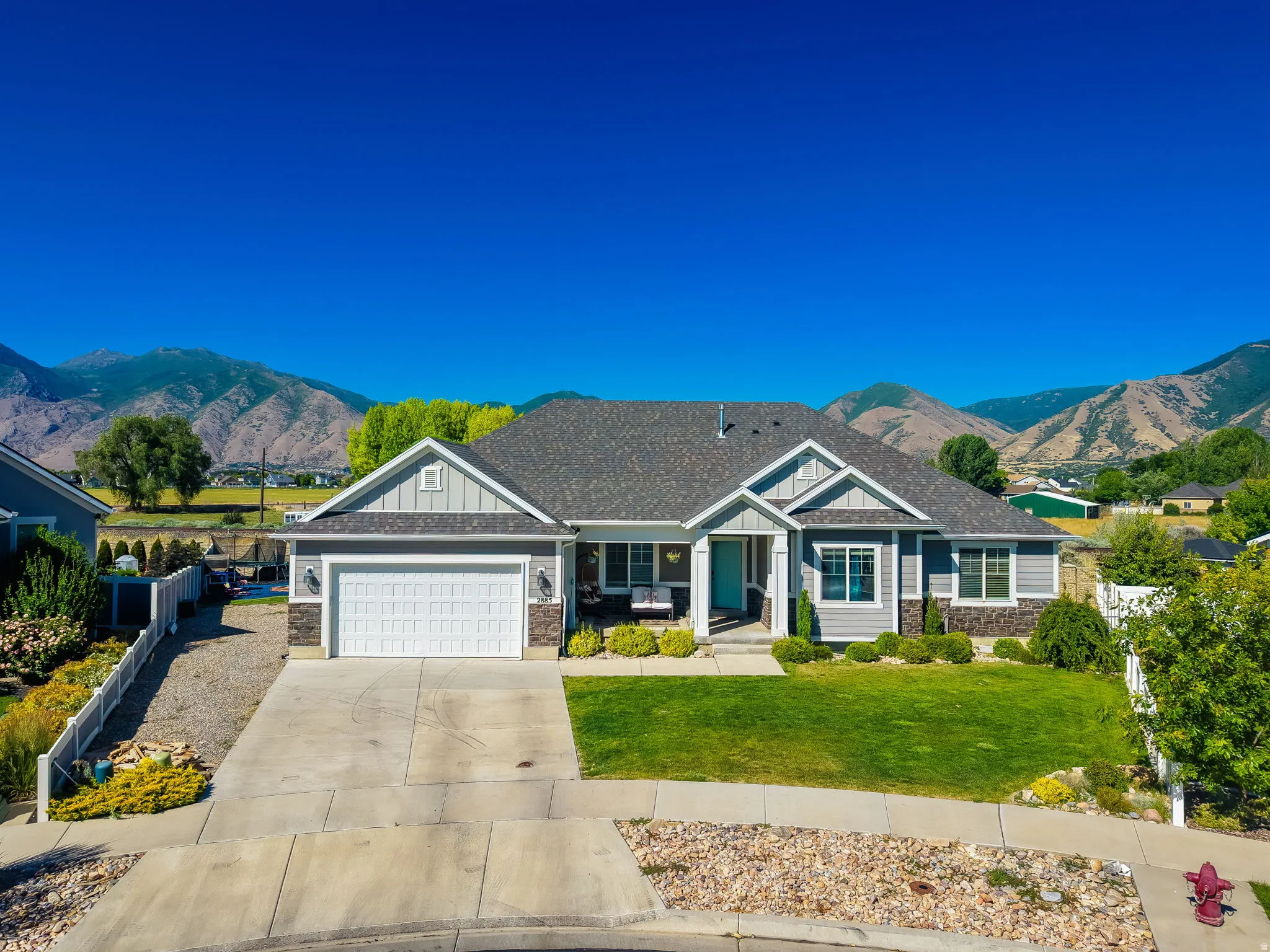 Ranch-style residence featuring a gray exterior with stone accents and a prominent front entry with a light blue door