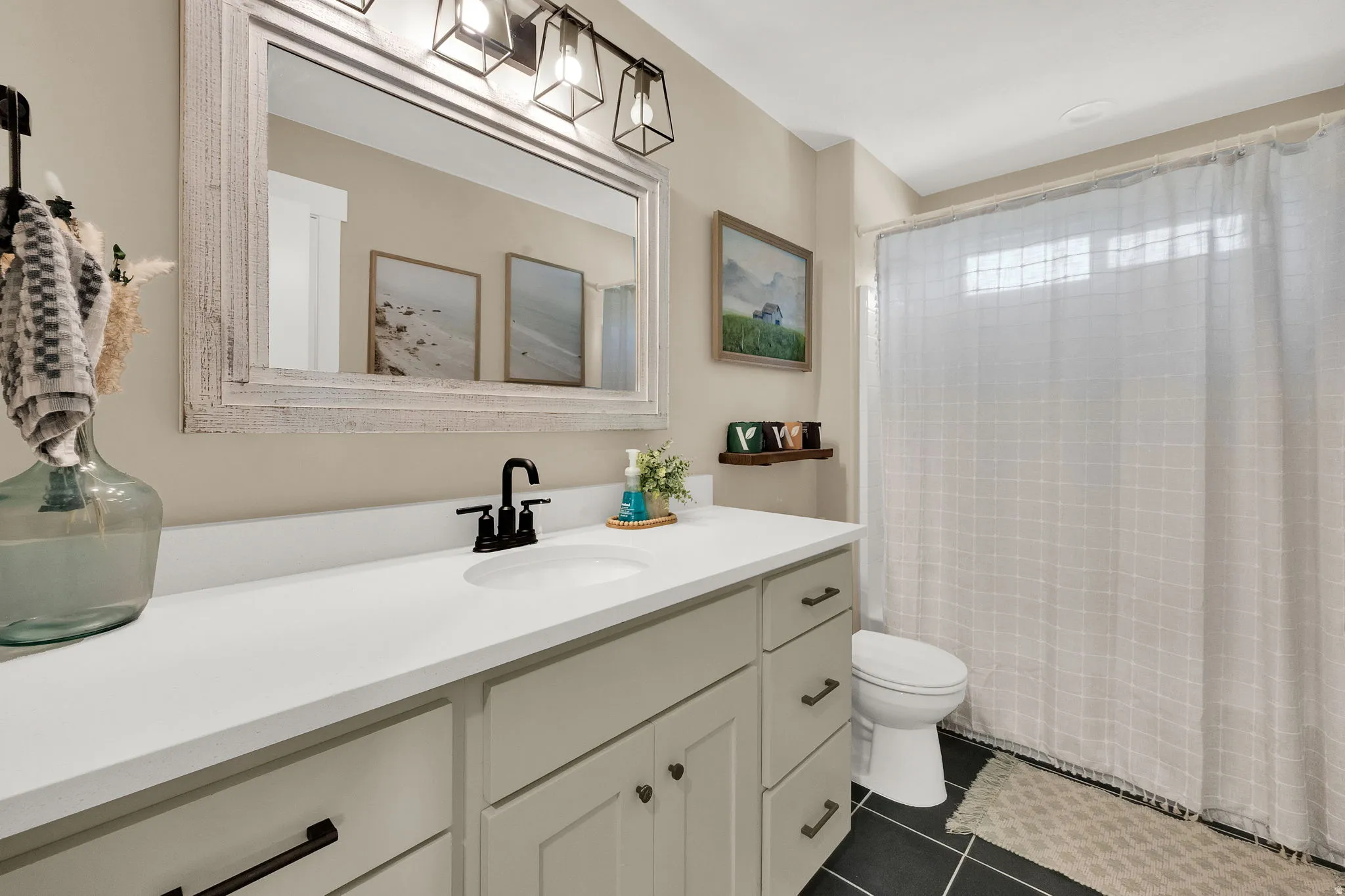 Bathroom featuring a single vanity with a white countertop, an undermount sink, and black hardware