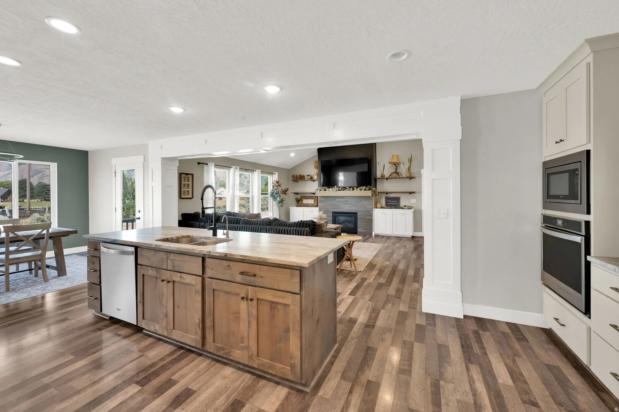 Spacious kitchen featuring a wood-finish island with integrated sink, stainless steel dishwasher, and light-toned countertop