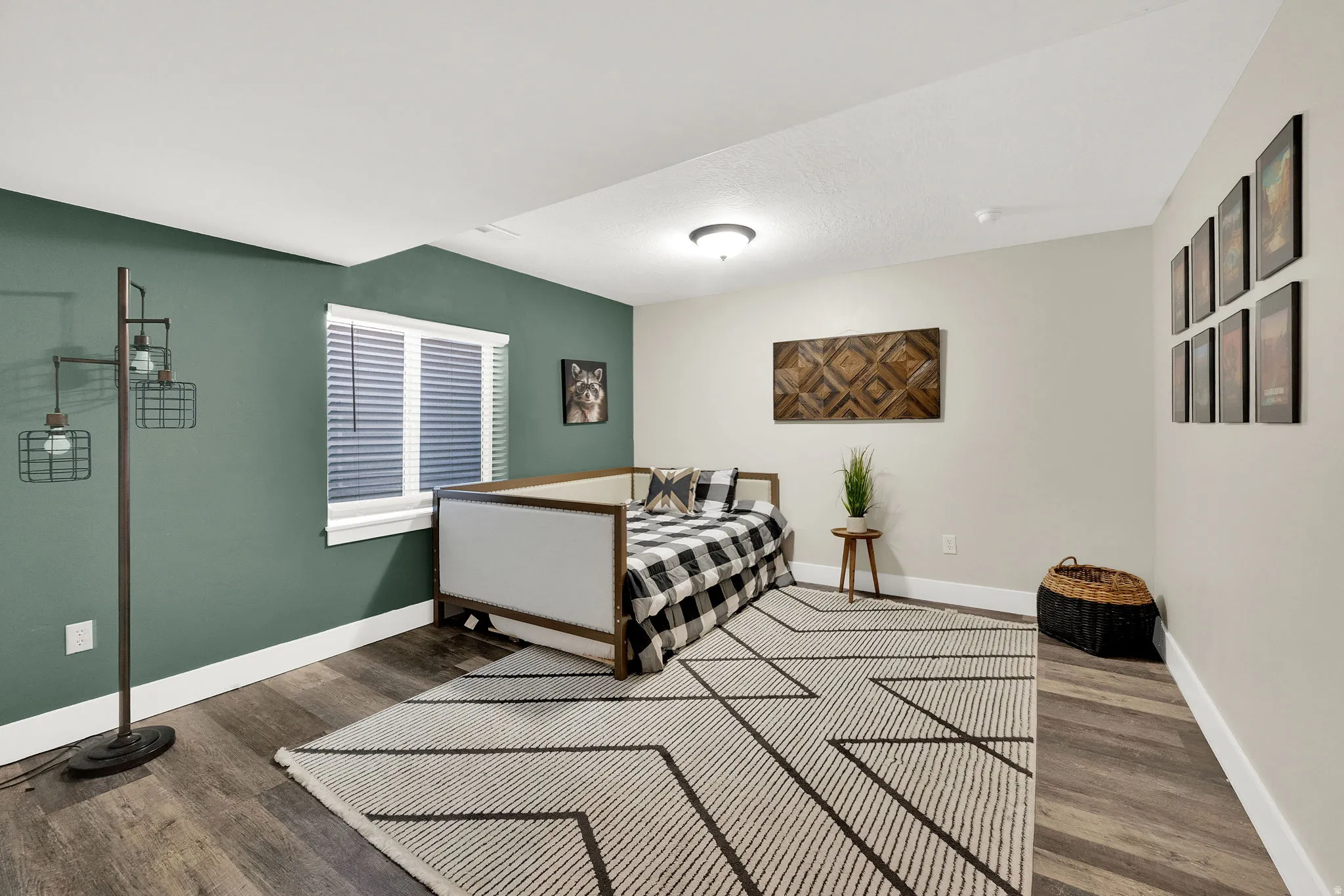 Spacious room featuring wood-finish flooring, a prominent accent wall, white trim, and a window with blinds
