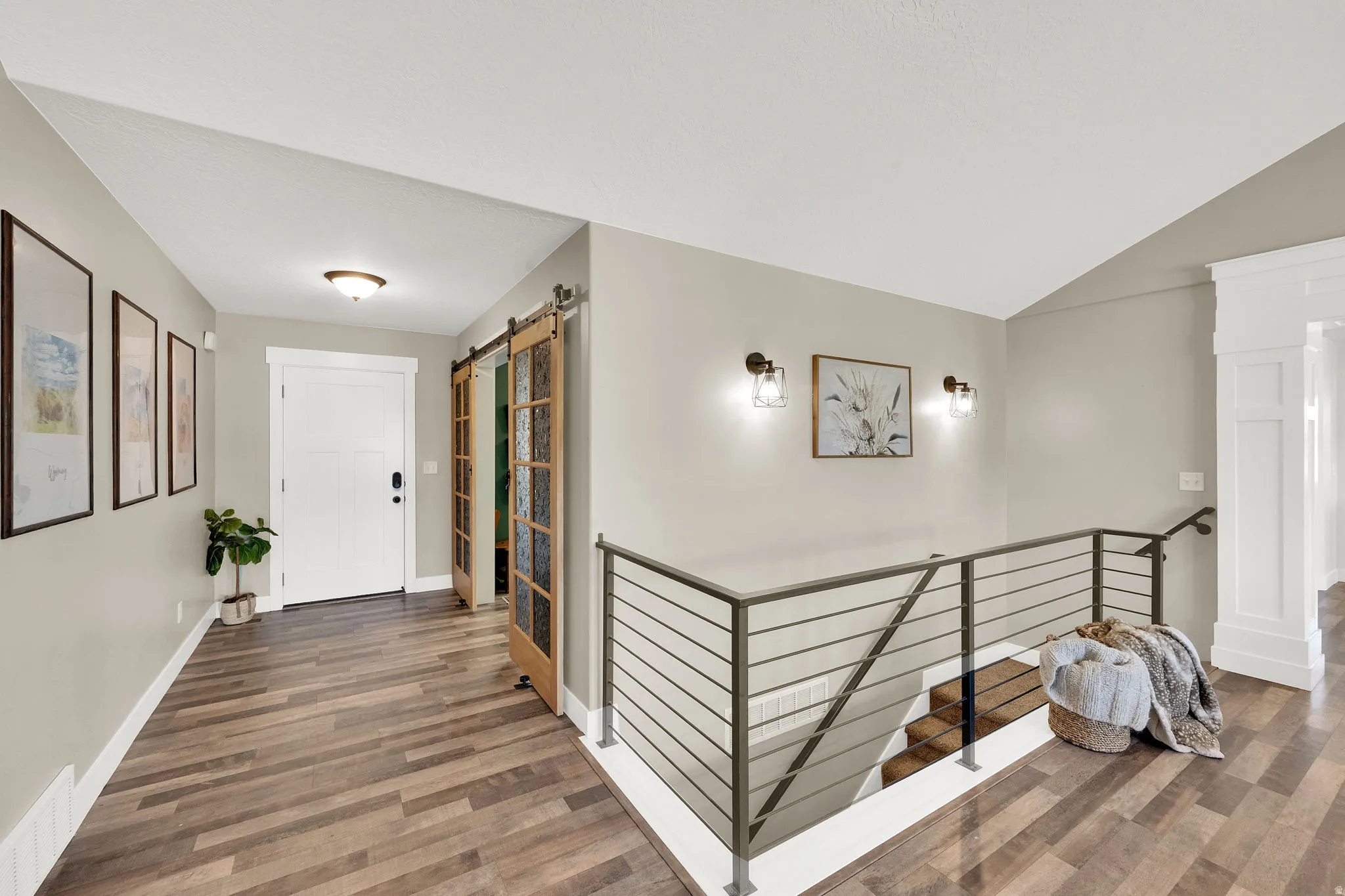 Foyer featuring wood-finish flooring, a white paneled entry door, and barn doors with frosted glass panels