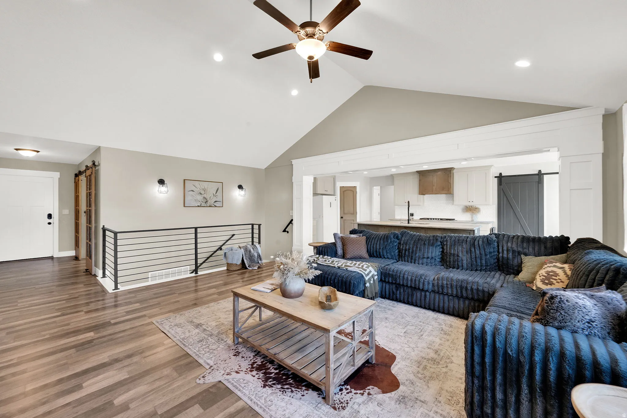 Vaulted ceiling with a ceiling fan, wood-finish flooring, recessed lighting, and a black metal railing
