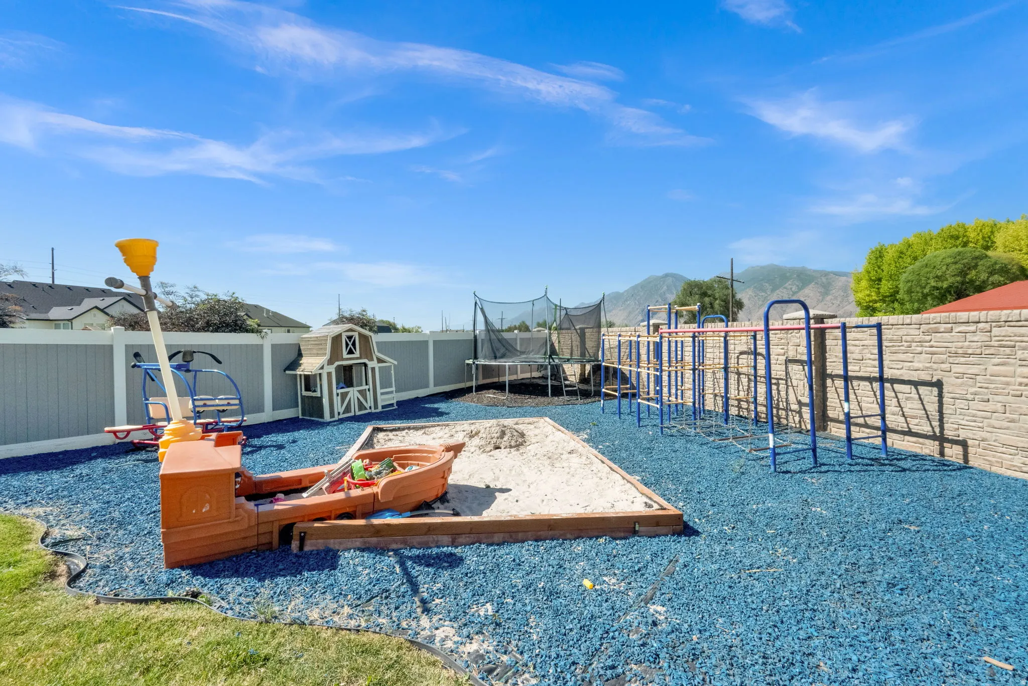Spacious backyard featuring blue rubber chip surfacing, a sandpit, and a trampoline