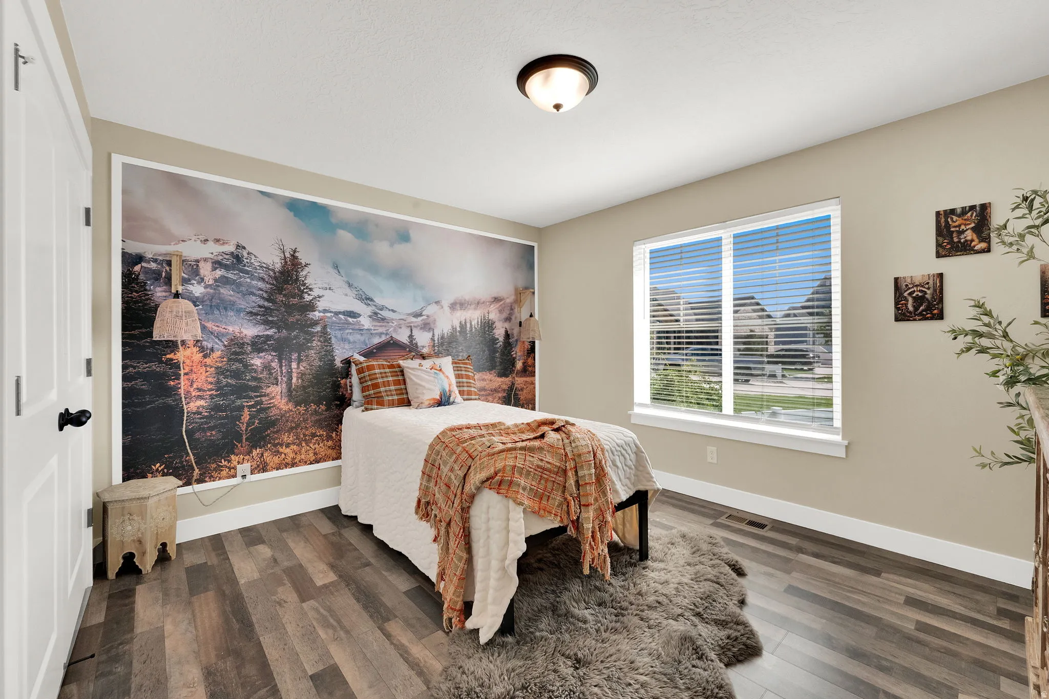 Bedroom featuring wood-finish flooring, a contemporary ceiling light fixture, and a large window with horizontal blinds