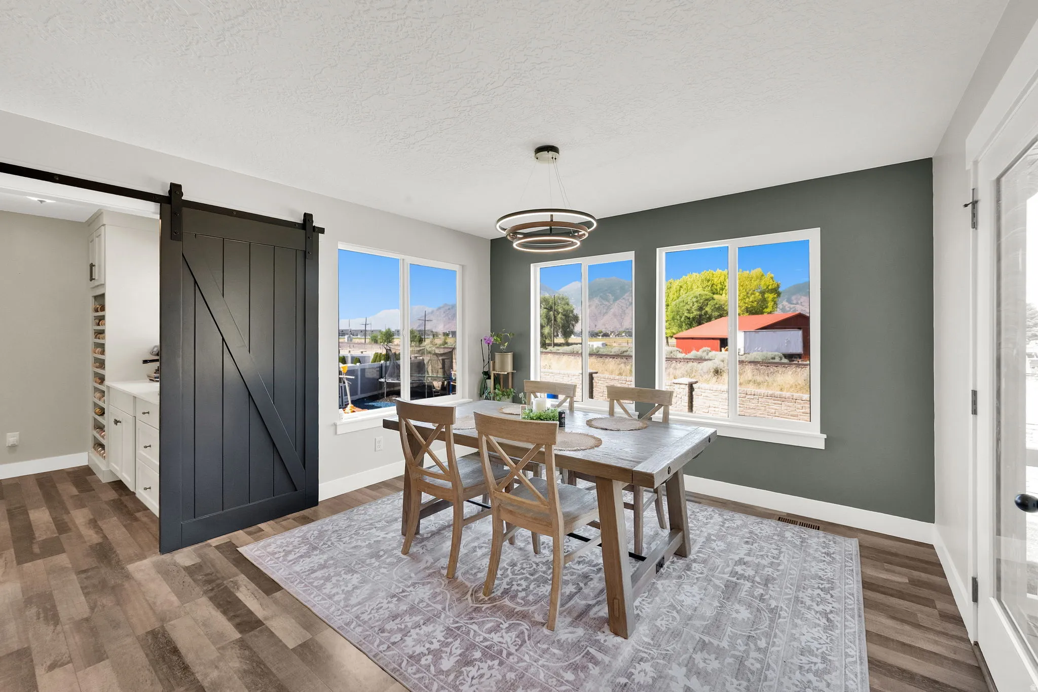 Dining area featuring wood-finish flooring, a contemporary chandelier, and three expansive windows