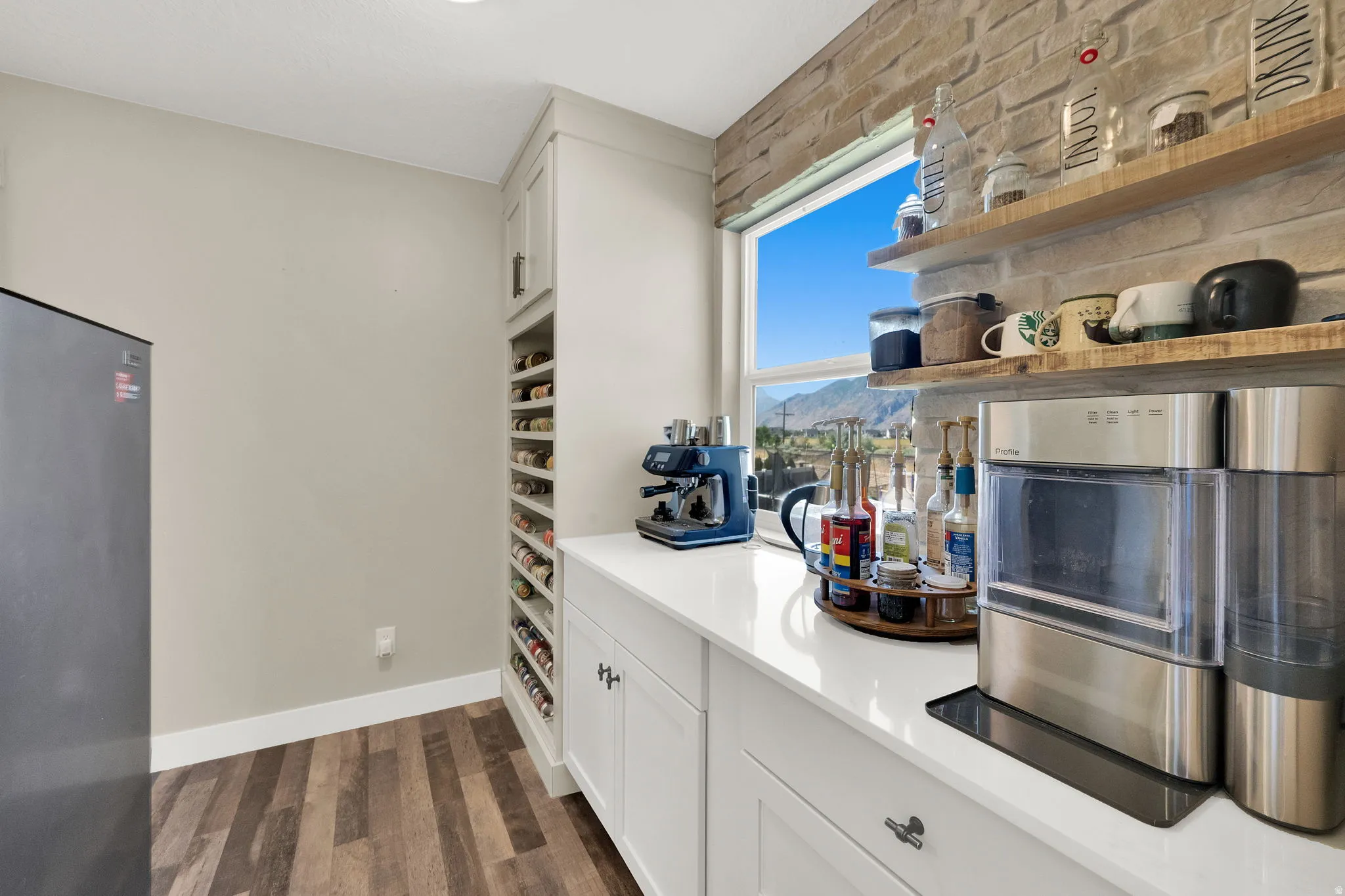 Kitchenette featuring white cabinetry, a built-in wine rack, wood-finish flooring, a quartz countertop, and a window with mountain scenery