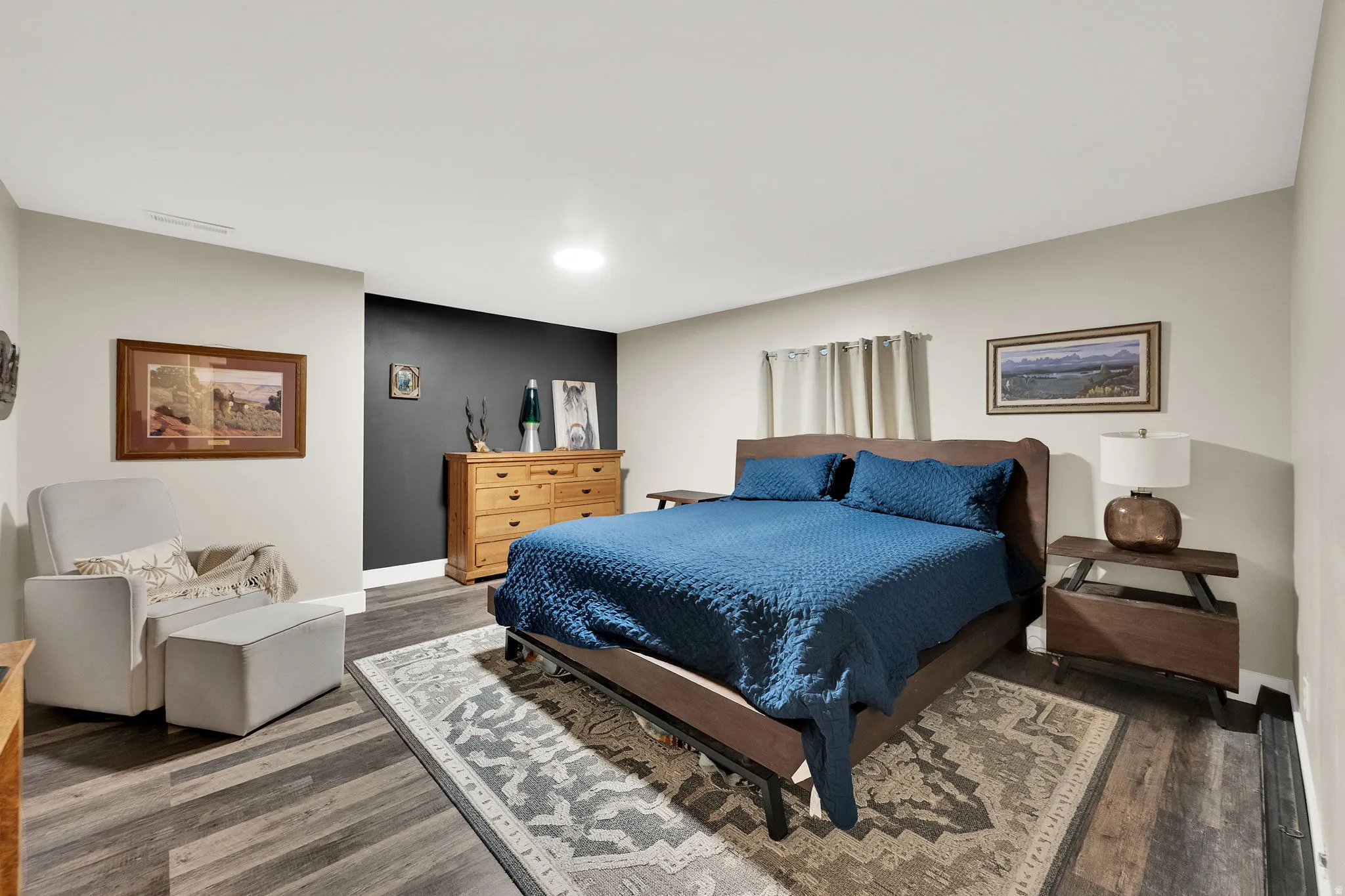 Spacious room featuring wood-finish flooring, a dark accent wall, and light-toned walls