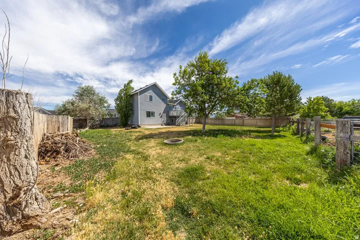 Expansive backyard featuring a partial wood privacy fence and mature trees