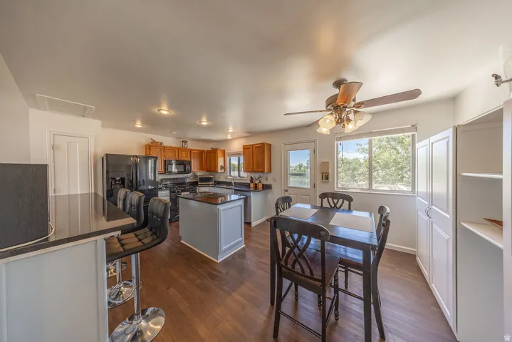 Open-concept kitchen and dining area featuring wood-finish flooring, recessed lighting, and a ceiling fan