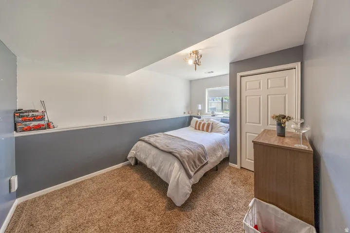 Carpeted room with a ceiling-mounted light fixture, a window, and a paneled closet door