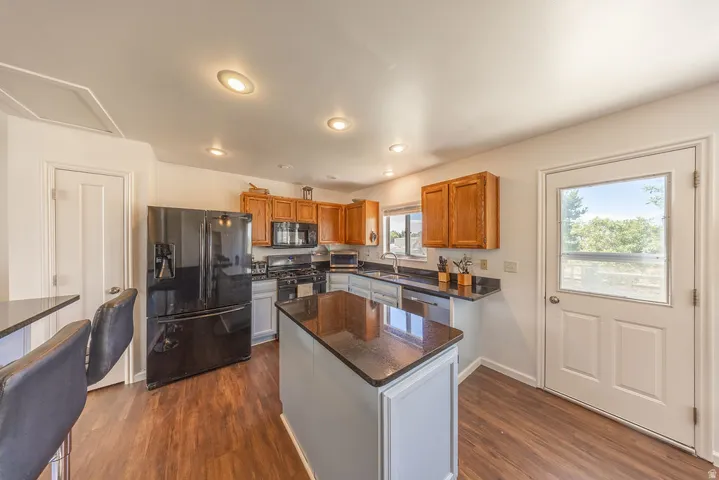 Kitchen featuring wood-finish flooring, recessed lighting, and a center island with a dark countertop