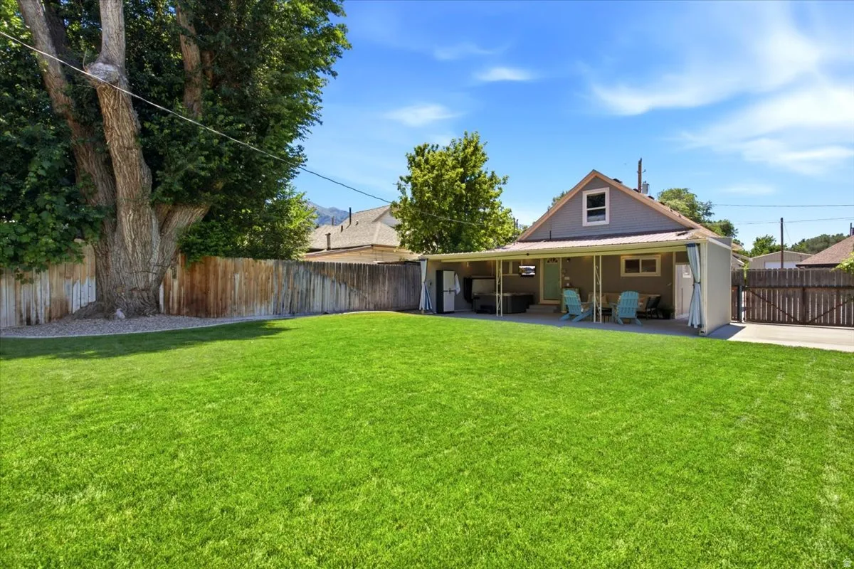 Back of house with LUSH LAWN! Enjoy the privacy, the hot tub, and mature landscaping.